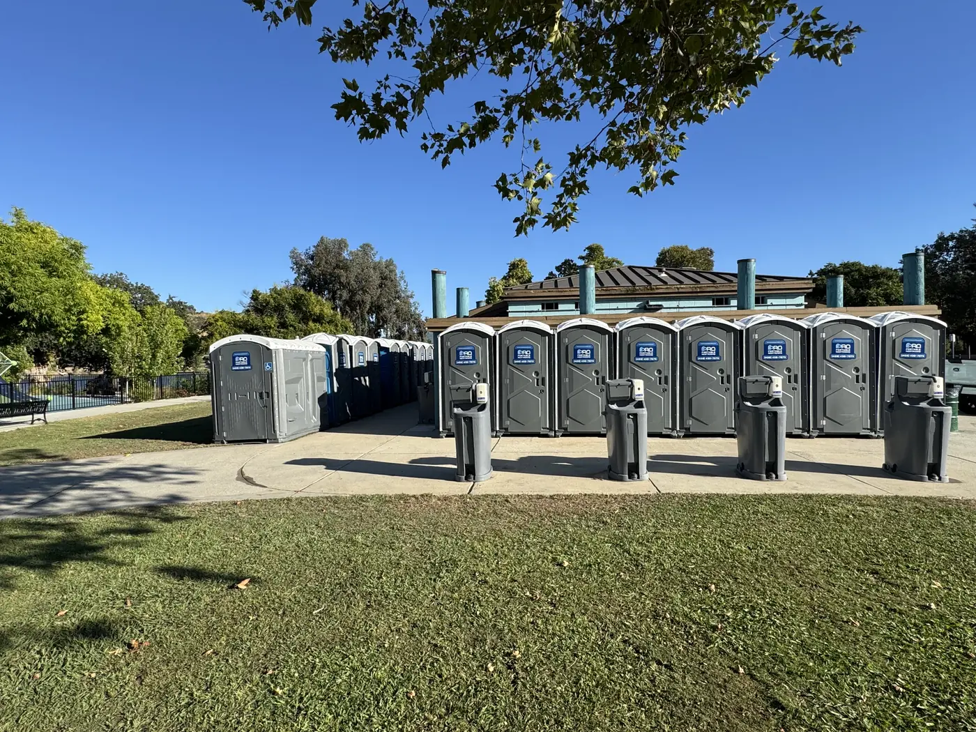 The finished row of portable restrooms and hand-wash stations seen from the park lawn