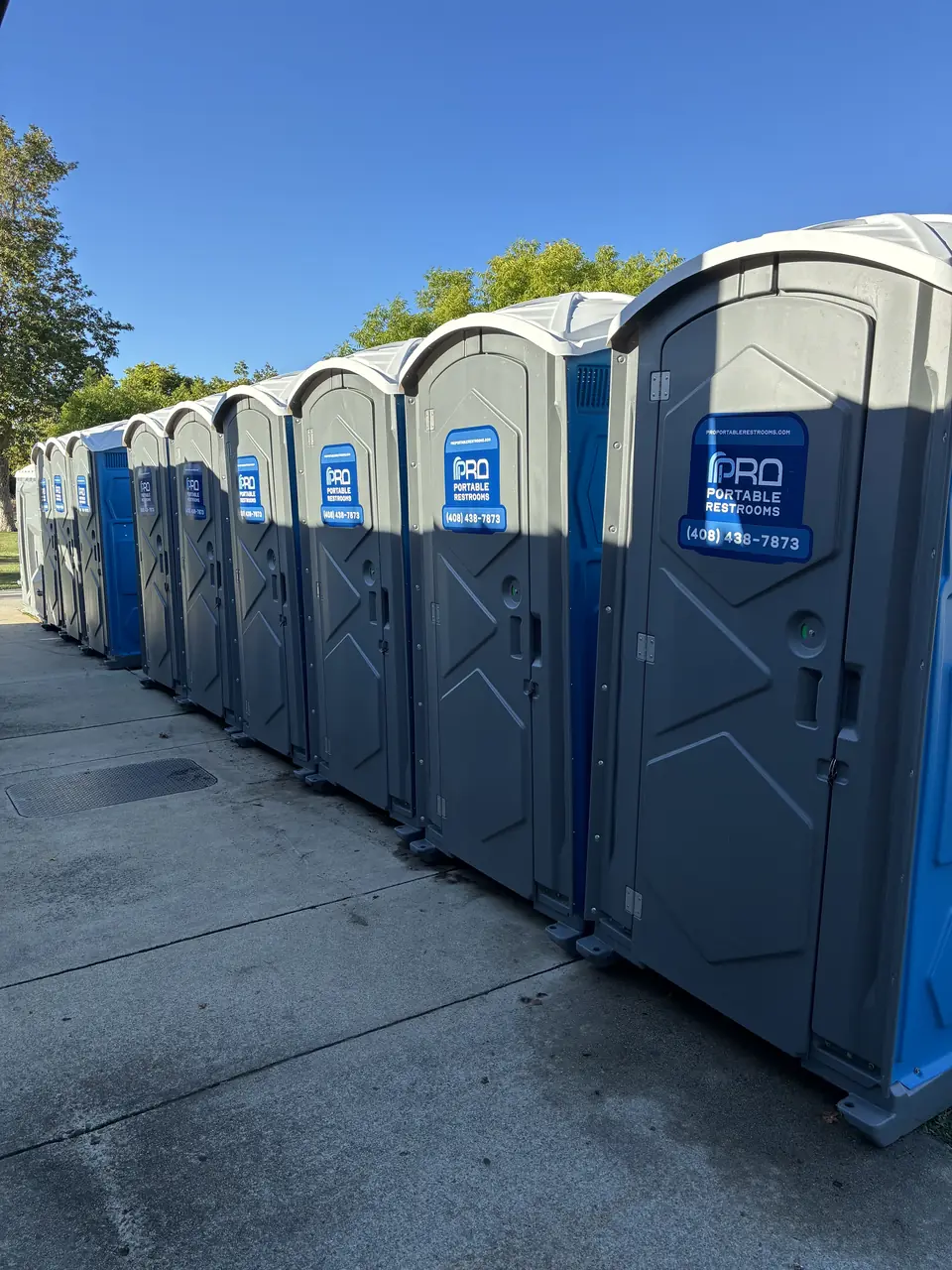 A long row of Pro Portable Restrooms units along a park walkway in San Jose