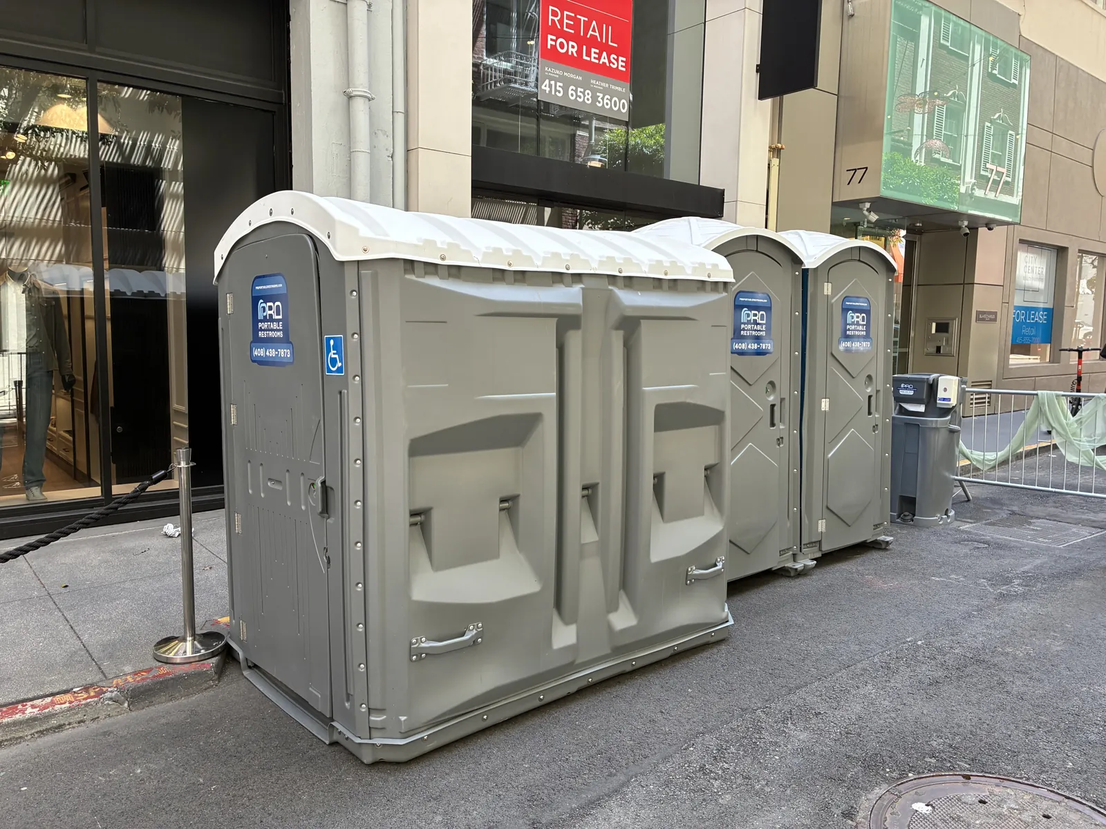 A row of Pro Portable Restrooms units, including an ADA unit, staged outside a Santa Clara storefront