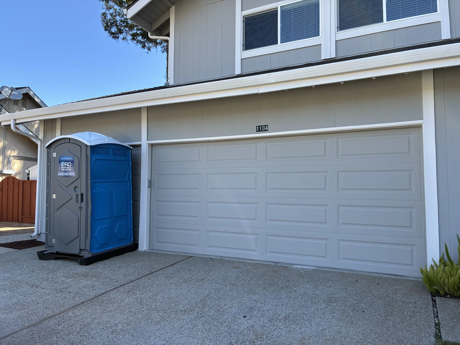 A clean Pro Portable Restrooms unit placed in front of a San Jose home garage