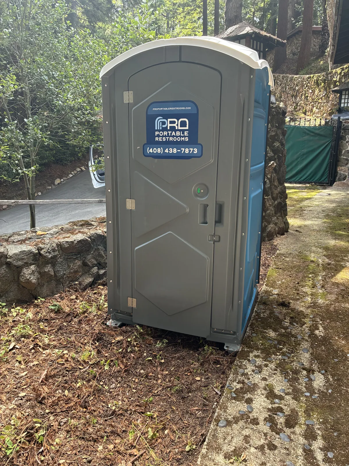 A clean Pro Portable Restrooms unit placed beside a garden path at an outdoor venue