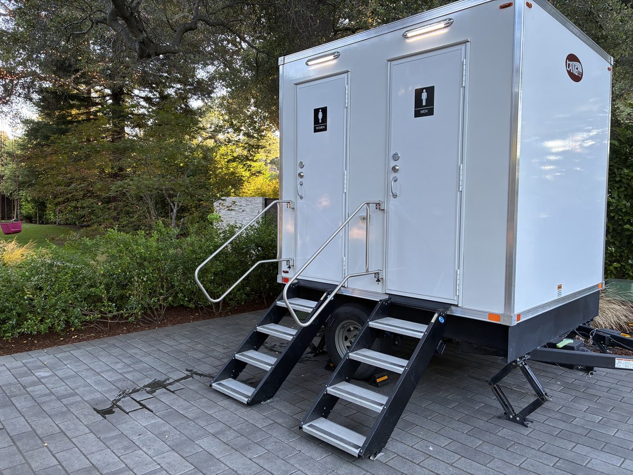 A Pro Portable Restrooms VIP restroom trailer with its steps down, set up on a paver patio